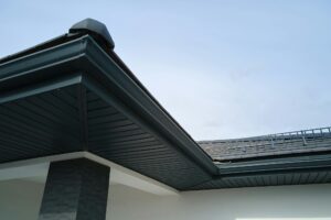 House corner with brown metal planks siding and roof with steel gutter rain system