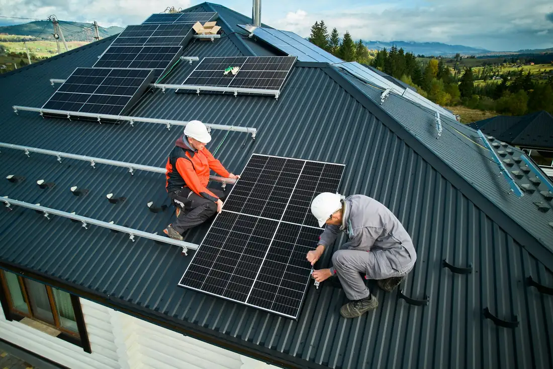 Technicians installing solar panels on a standing seam metal roof